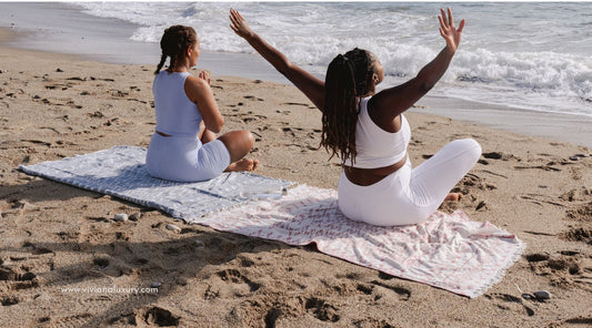 Two women relaxing on the beach with yoga and meditation